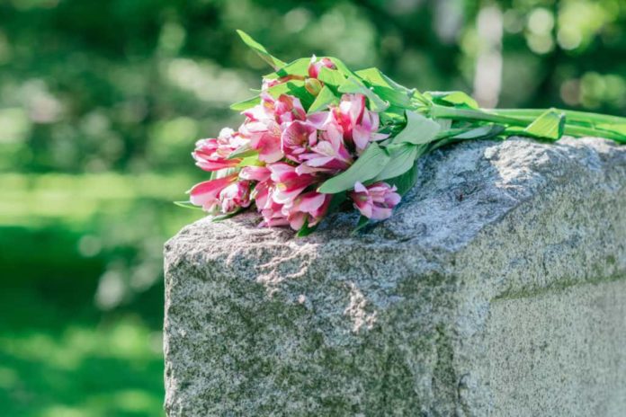 Flowers placed on top of a tombstone.