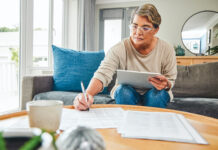 woman using a digital tablet while going through paperwork at home
