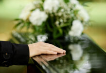 Female hand on black coffin