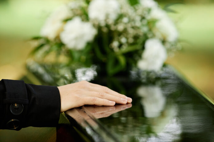 Female hand on black coffin
