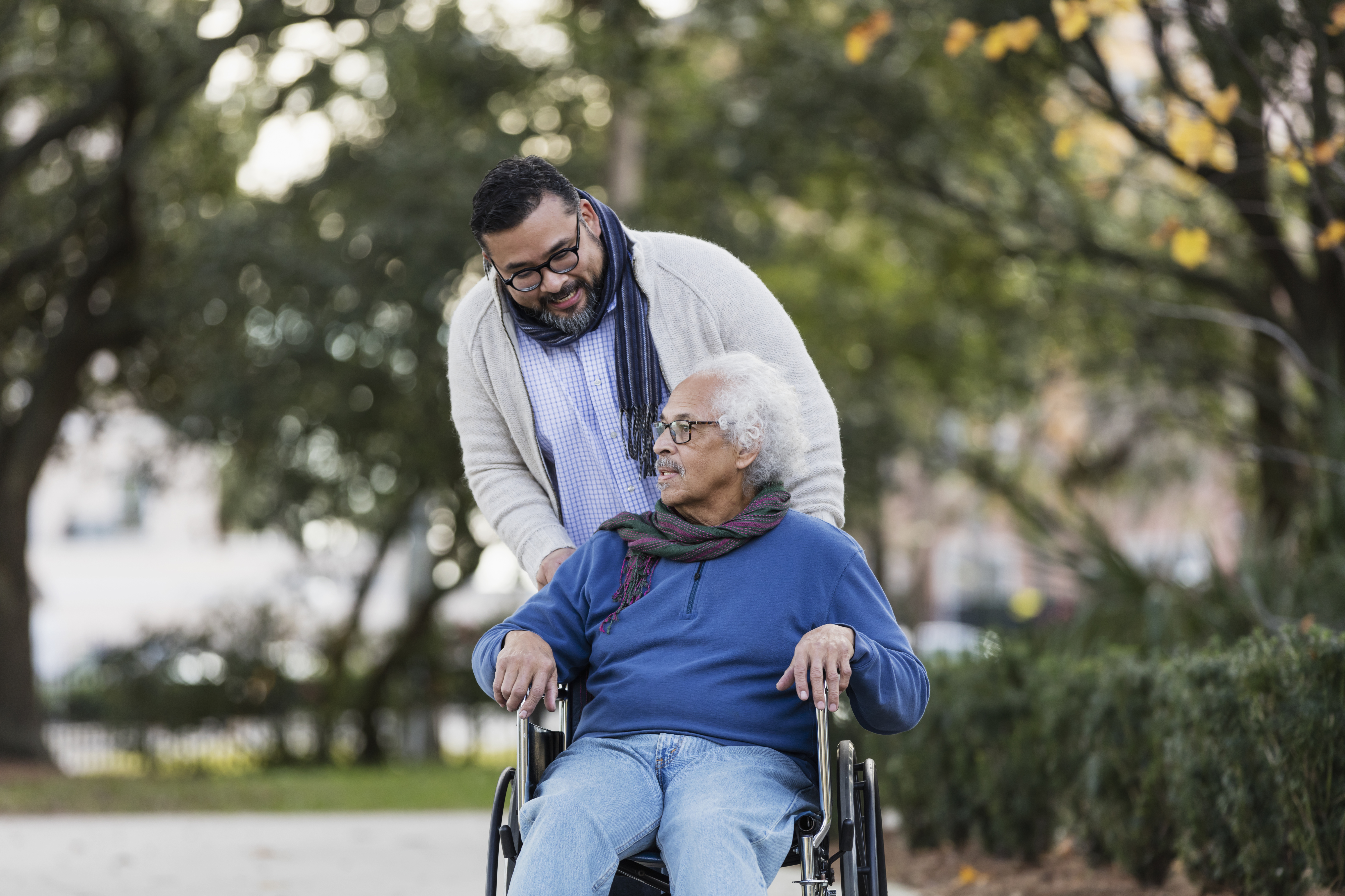 Senior man in wheelchair, with adult caregiver