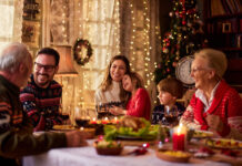 Cheerful multi-generation family communicating while enjoying in Christmas meal at dining table.