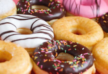 assorted donuts with chocolate frosting, topping sprinkles donuts Colorful variety and Variety of flavors mix of multi colored sweet donuts with frosted sprinkled on pink background. top view
