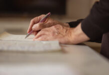 Writer of Holographic Will Pleads for No Fighting or Unpleasantness Close up shot of a senior man hands, writing in his old notebook.