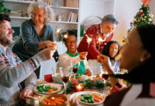 Multigenerational family holding sparklers and singing together, full of festive joy and energy.