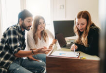 Financial advisor consultant is showing trends to the clients. They are in the office.